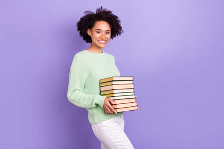 Photo of cheerful happy joyful dark skin woman smile good mood hold hands books isolated on purple...