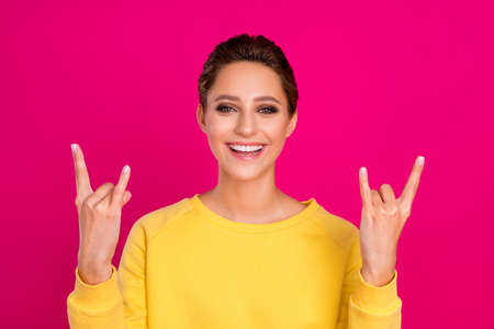 Photo of shiny funky young woman dressed yellow pullover showing hard rock sign smiling isolated...