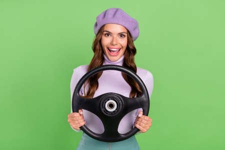 Portrait of astonished carefree girl hands hold wheel open mouth isolated on green color backgroundの写真素材