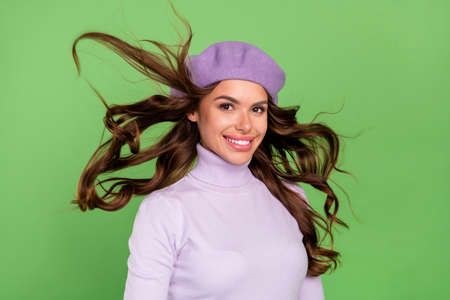 Portrait of adorable satisfied girl look camera toothy smile flying hairdo isolated on green color backgroundの写真素材