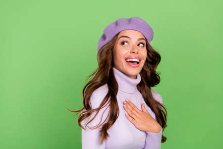 Profile portrait of fascinated adorable person arm on chest look interested empty space isolated on green color backgroundの写真素材