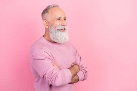 Profile photo of funny grey hair mature man crossed arms look empty space wear pink sweater isolated on pastel backgroundの写真素材