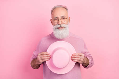 Photo of cool grey hair elder man hold cap wear eyewear sweater isolated on pink backgroundの写真素材