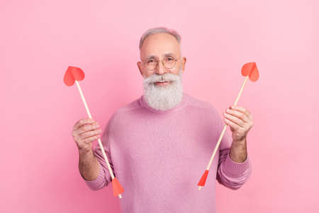 Photo of positive grey beard hair old man hold arrows wear eyewear sweater isolated on pink backgroundの写真素材