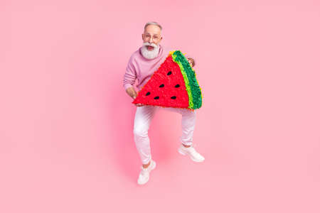 Photo of pretty funky gentleman wear sweater spectacles jumping holding watermelon slice isolated pink color backgroundの写真素材