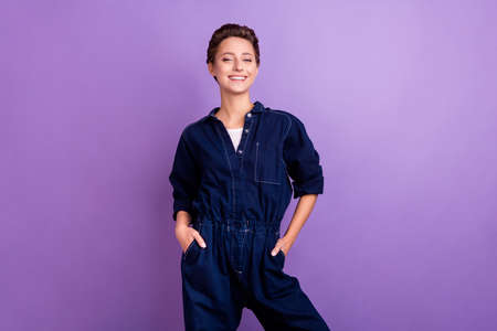 Photo of cool young short hairdo lady wear jeans overall isolated on violet color backgroundの写真素材