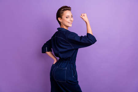 Profile side photo of smiling confident strong brave woman raise fist feminism isolated on purple color backgroundの写真素材