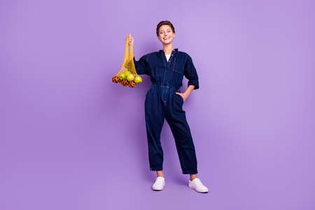 Full size photo of young smiling girl advertise recommend using reusable net bag isolated on violet color backgroundの写真素材