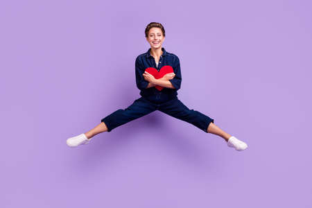Full size photo of young lovely smiling girl jumping hug red paper heart valentine day isolated on purple color backgroundの写真素材