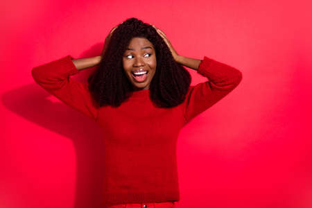 Photo of excited funny dark skin woman dressed casual pullover arms head looking empty space isolated red color backgroundの写真素材