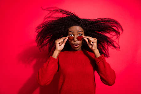 Photo of young afro girl amazed shocked surprised fake novelty news reaction isolated over red color backgroundの写真素材