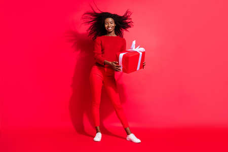 Full length photo of young black girl happy positive smile gift celebration birthday surprise isolated over red color backgroundの写真素材