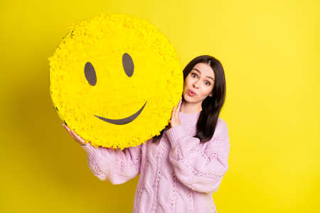 Hooray young woman hold big smile toy wear rose pullover isolated on vivid yellow color backgroundの写真素材