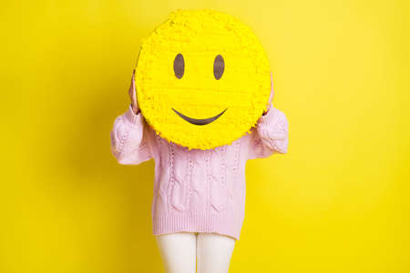 Big smile toy hide lady face wear rose pullover pants isolated on vivid yellow color backgroundの写真素材