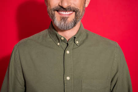 Cropped photo of optimistic age brunet man wear khaki shirt isolated on red color backgroundの写真素材