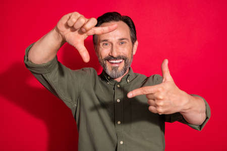 Photo of cool mature brunet man hands face wear green shirt isolated on red color backgroundの写真素材