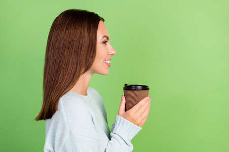 Profile photo of funky young brunette lady drink coffee wear blue jumper isolated on green color backgroundの写真素材