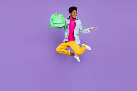 Photo of promoter guy jump hold rucksack hand empty space wear blue shirt isolated violet color backgroundの写真素材