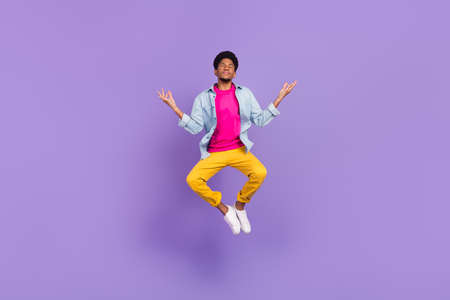 Photo of peaceful guy jump yoga practice close eyes wear blue shirt pants shoes isolated purple color backgroundの写真素材