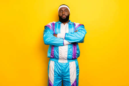 Photo of cute serious dark skin man wear blue suit headband hands folded isolated yellow color backgroundの写真素材