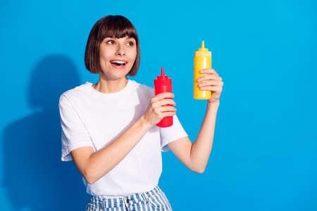 Photo portrait pretty girl smiling keeping ketchup mustard looking copyspace isolated vibrant blue color backgroundの写真素材