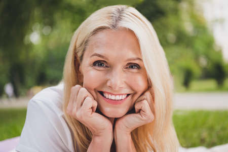 Photo of mature sweet blond lady wear white t-shirt in park aloneの写真素材