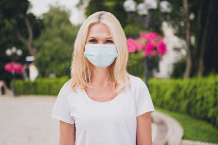 Photo of aged blond lady wear mask white t-shirt in park aloneの写真素材