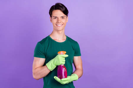Photo of attractive positive cheerful young man hold cleaner chemical isolated on purple color backgroundの写真素材