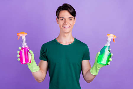 Photo of happy positive cheerful young man hold bottles cleaner housekeeper isolated on purple color backgroundの写真素材