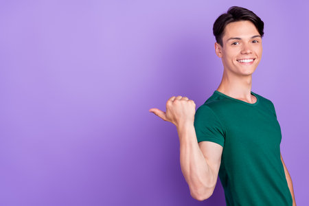 Photo of attractive young happy positive man point finger empty space sale news isolated on purple color backgroundの写真素材