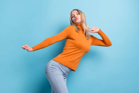 Photo of funny cute young lady wear orange sweater dancing lips pouted isolated blue color backgroundの写真素材