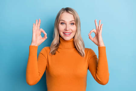 Photo of charming cheerful young woman make fingers okay signs recommend isolated on blue color...