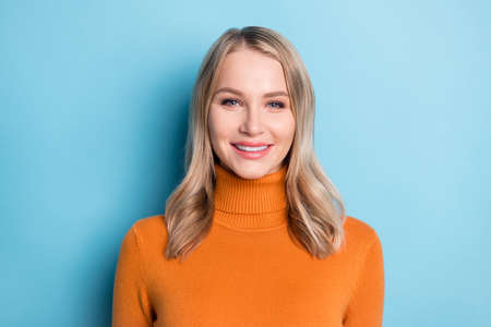 Photo of charming sweet young woman dressed orange pullover smiling isolated blue color backgroundの写真素材