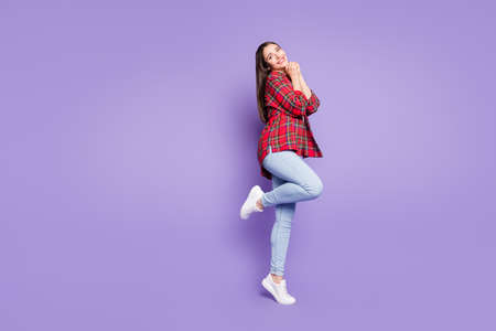 Full length photo of sweet brunette hairdo young lady hold hands wear red shirt jeans isolated on purple color backgroundの写真素材