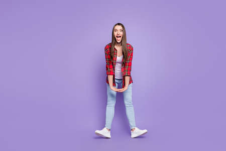 Full body photo of cute brunette hairdo young lady hold hands yell wear red shirt jeans isolated on purple color backgroundの写真素材