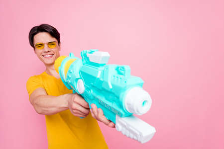 Photo of young guy happy positive smile play game water gun trip beach have fun isolated over pastel color backgroundの写真素材