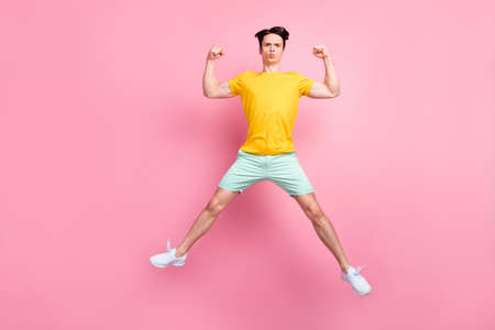 Photo of sporty strong energetic guy jump show biceps wear yellow t-shirt isolated on pink...
