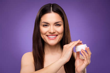 Photo of excited adorable young lady wear nothing holding body cream smiling isolated purple color backgroundの写真素材