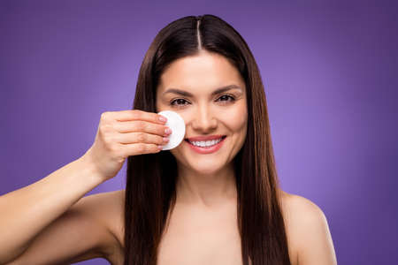 Photo of cute charming mature woman  shoulders smiling removing make up cotton pad isolated violet color backgroundの写真素材