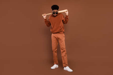 Full body photo of agressive short hairdo young guy hold bit dress spectacles sportswear trousers sneakers isolated on brown backgroundの写真素材