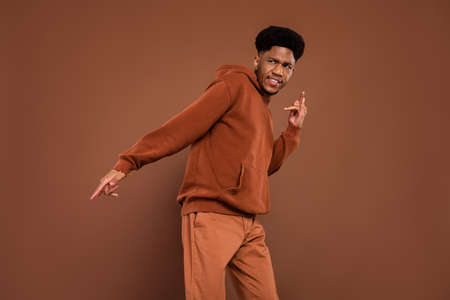 Photo of cool handsome african guy dance look empty space wear sweatshirt pants isolated on brown backgroundの写真素材