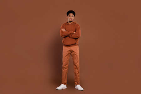 Photo of self-assured successful african guy crossed hands wear sweatshirt pants sneakers isolated on brown backgroundの写真素材