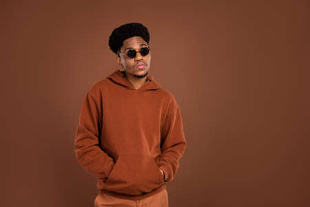 Photo of serious brunet hairdo young guy look empty space dress spectacles sportswear isolated on brown color backgroundの写真素材