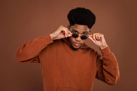 Photo of cool brunet hairdo young guy touch spectacles dress sportswear isolated on brown color...