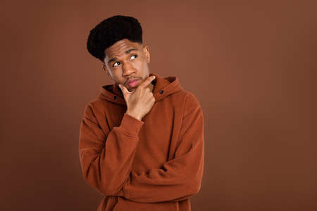 Photo of doubtful brunet hairdo millennial guy look empty space dress sportswear isolated on brown color backgroundの写真素材