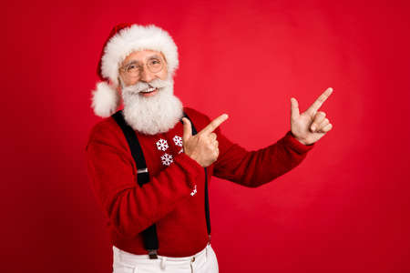 Portrait of attractive cheerful Santa demonstrating copy space ad sale discount isolated over bright...