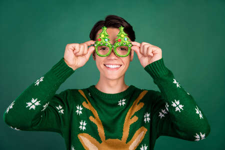 Photo of cheerful glad funny guy beaming smile wear glasses deer ornament pullover isolated green...