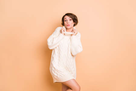 Photo portrait of pretty girl in oversize sweater sending air kiss isolated on pastel beige color backgroundの写真素材