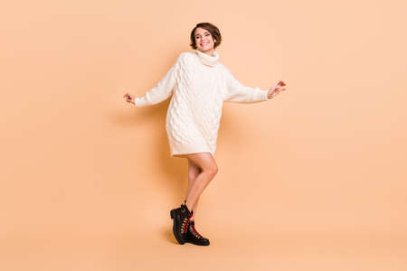 Full length body size photo of girl with bob hair dancing on discotheque entertaining isolated on pastel beige color backgroundの写真素材