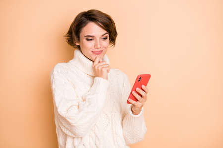 Photo of thoughtful minded woman look phone imagine message post blog isolated on beige color backgroundの写真素材